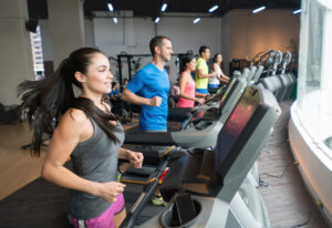 Athletic people working out at the gym running on the treadmills and looking very happy - fitness concepts